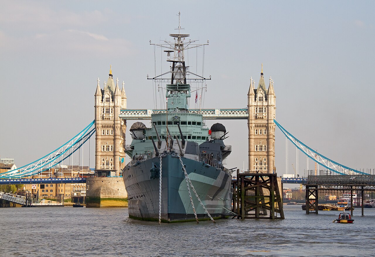 HMS Belfast moored on the Thames, framed between the towers of Tower Bridge